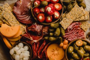 a farm-to-table charcuterie board of olives, cured meats, stuffed peppers, and more