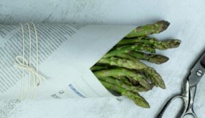 fresh asparagus wrapped in newspaper with string