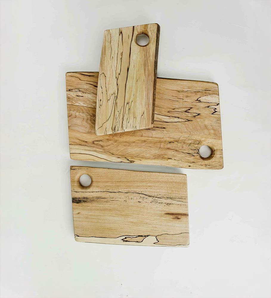 Three spalted maple cutting boards with natural grain patterns and hand-drilled hanging holes, arranged flat on a white background.