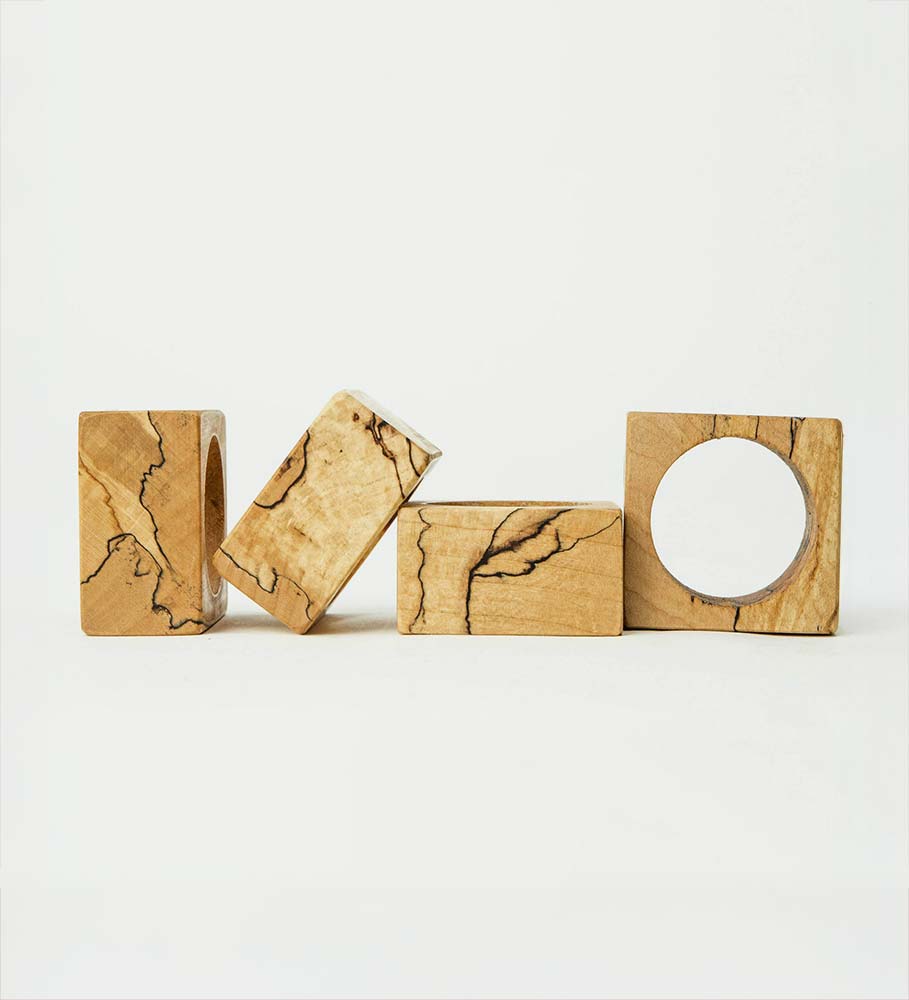 Set of four spalted maple napkin rings in geometric shapes, each showing unique grain lines and spalting marks.