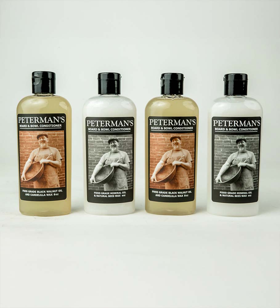 Four bottles of Peterman’s Board & Bowl Conditioner lined up in a row, featuring black-and-white portraits of the maker.
