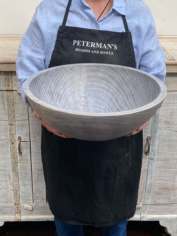 An employee at Spencer Peterman holding a 15-inch Driftwood Oak round bowl, showcasing the soft matte finish and organic grain of aged oak.