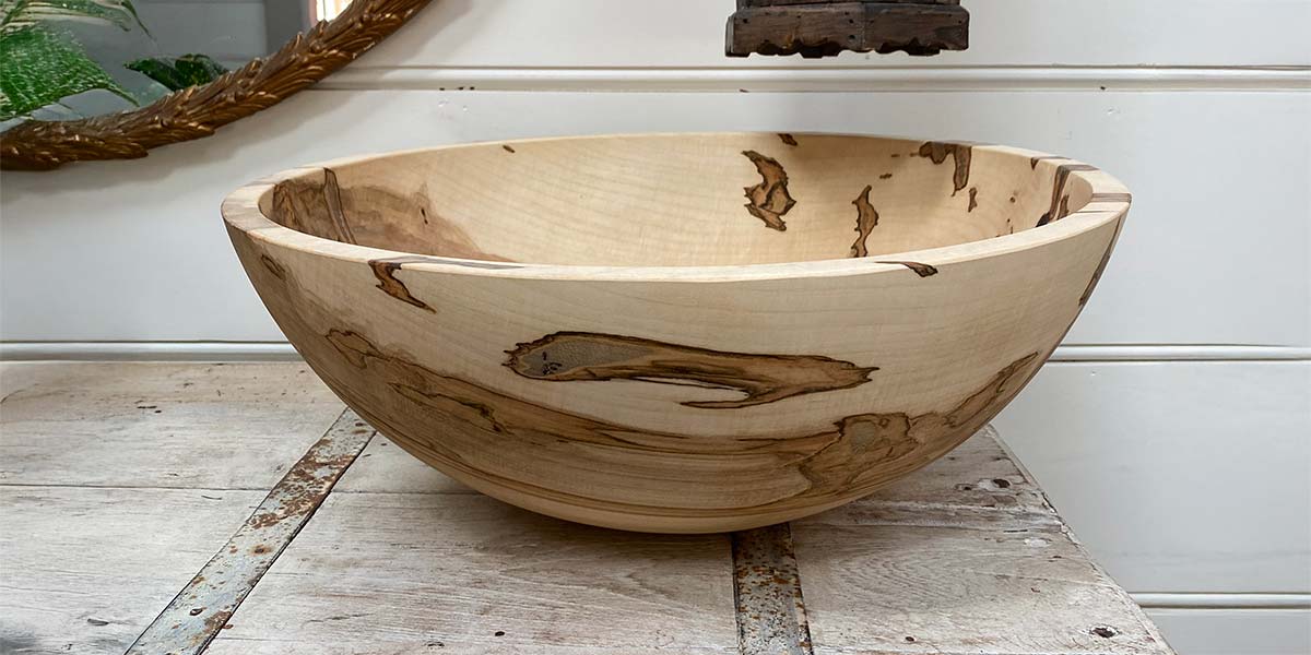Hand-turned ambrosia maple bowl showing subtle gray beetle streaks and natural wood grain